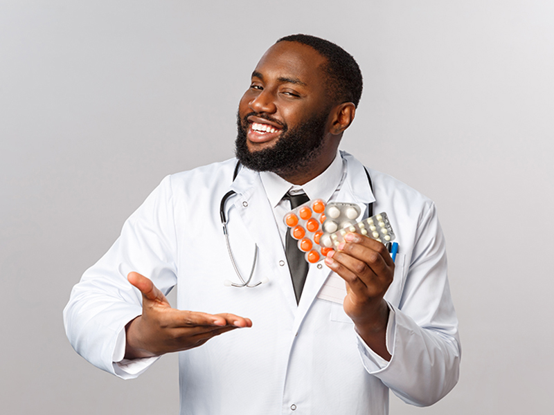 Flu, disease, healthcare and medicine concept. Happy african-american male doctor in white coat present new drugs, cure from disease or viruses, showing pills guarantee good quality of treatment.